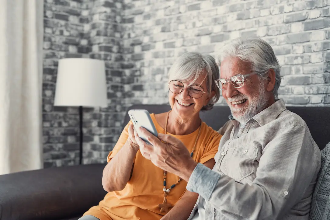 Elderly grandfather and grandmother spend time having fun using smartphone apps, middle-aged wife enjoy online entertainments, taking selfie with old husband, older generation and modern tech concept